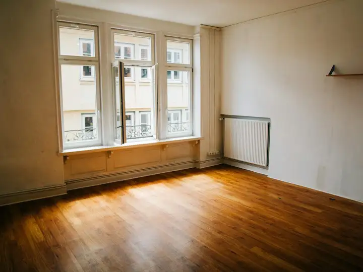 Empty room with wooden floor and tall windows